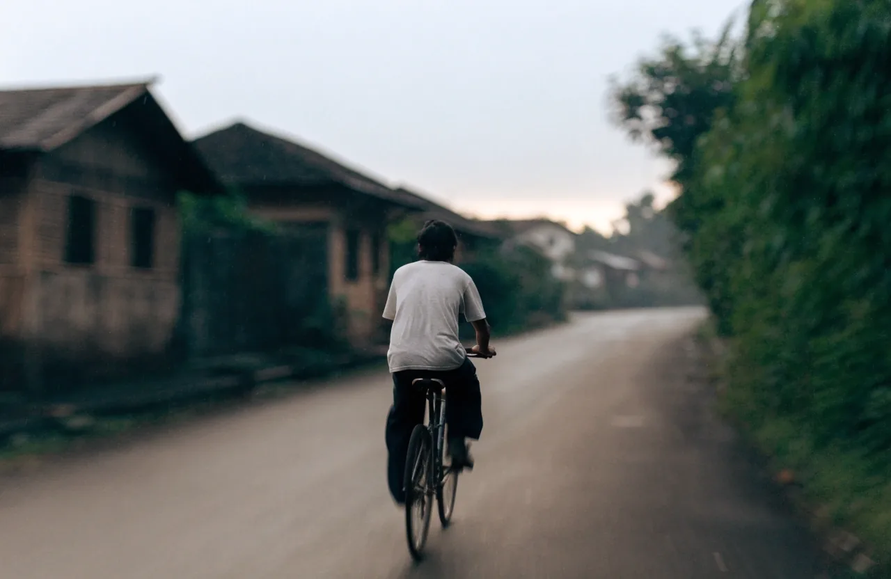 Man seen from behind walking along a shaded lane in early morning light